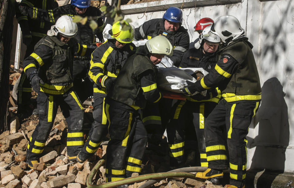 Firefighters carry the body of a person killed after a drone fired on buildings in Kyiv, Ukraine, Monday, Oct. 17, 2022. Waves of explosive-laden suicide drones struck Ukraine's capital as families were preparing to start their week early Monday, the blasts echoing across Kyiv, setting buildings ablaze and sending people scurrying to shelters. (AP Photo/Yevhenii Zavhorodnii)