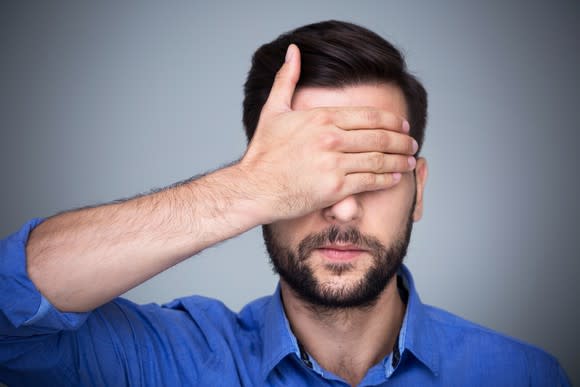 Young man covering his eyes with a hand.