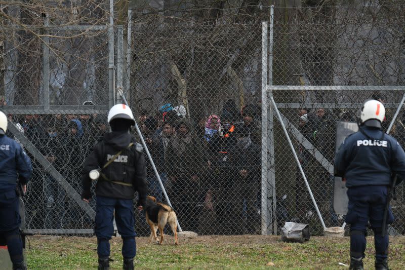 Migrants who want to cross into Greece from Turkey are gathered at the borderline as Greek riot police stand guard, at the closed Kastanies border crossing with Turkey's Pazarkule, in the region of Evros
