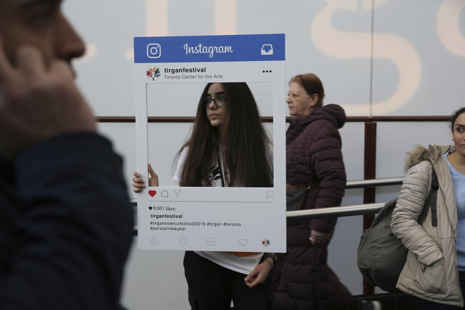 In this Saturday, March 9, 2019, Parmida Tahani, holds an Instagram frame inviting the visitors to share their photos in social media during the Tirgan Nowruz Festival in Toronto, Canada. Parmida, 15, has migrated to Canada from Tehran, Iran, about 2 years ago and has joined the festival as a volunteer. The event aims to preserve and celebrate Iranian and Persian culture, said festival CEO Mehrdad Ariannejad. Among those who attended were second-and third-generation immigrants, many of whom have never been to Iran or have not been there since leaving the country following the 1979 Islamic Revolution. (AP Photo/Kamran Jebreili)