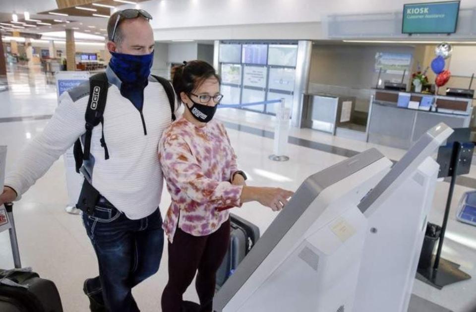 Shaleen Ague of Cedar Rapids, Iowa, checks herself and her husband, Joshua, in for their flight at the American Airlines kiosk at Eastern Iowa Airport in southwest Cedar Rapids, Iowa, on Wednesday, Nov. 4, 2020.