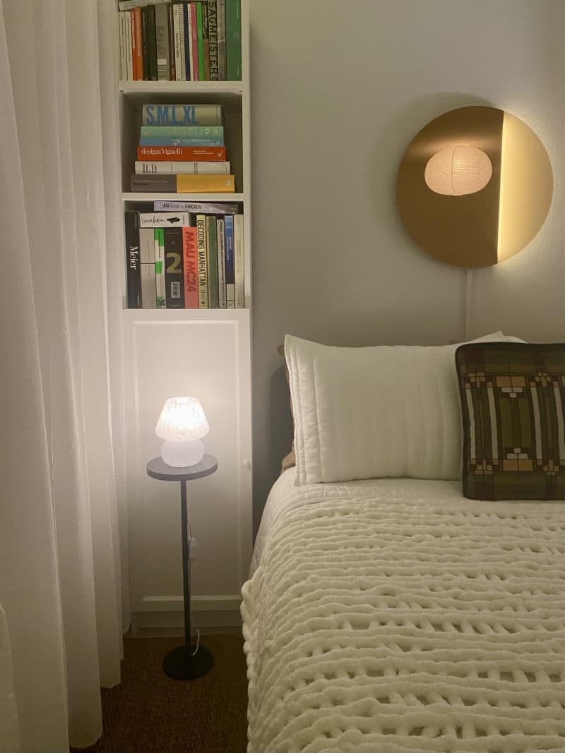 Built-in bookshelf next to a bed with wall-mounted circular