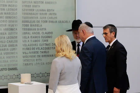 Israeli Prime Minister Benjamin Netanyahu and his wife Sara, alongside Agustin Zbar (R), President of the Argentine Israeli Mutual Association (AMIA) Jewish community center, stand in front of a wall with names of the victims of the 1994 AMIA bombing in Buenos Aires, Argentina September 11, 2017. Embassy of Israel in Buenos Aires/Handout via REUTERS