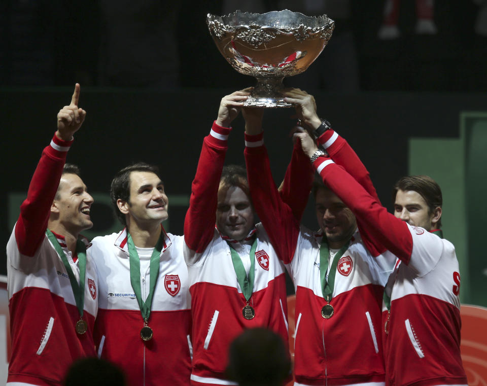 FILE - Swiss team, from left, Marco Chiudinelli, Roger Federer, coach Severin Luthi , Stanislas Wawrinka, and Michael Lammer hold the trophy after winning the Davis Cup final at the Pierre Mauroy stadium in Lille, northern France, Sunday, Nov. 23, 2014. Federer announced Thursday, Sept.15, 2022 he is retiring from tennis. (AP Photo/Peter Dejong, File)