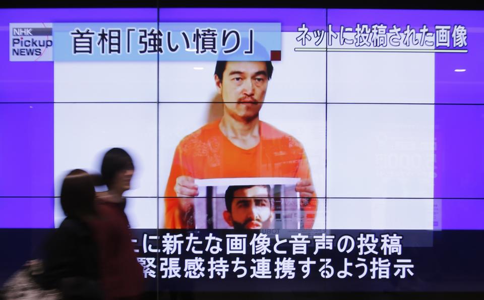 People walk past television screens displaying a news program, about an Islamic State video showing Japanese captive Kenji Goto, on a street in Tokyo January 28, 2015. Jordan said on Wednesday it was willing to hand over an Iraqi woman jailed for her role in a 2005 suicide bomb attack if a Jordanian pilot captured by Islamic State was released. Government spokesman Mohammad al-Momani made no mention of Japanese hostage Kenji Goto, a veteran war reporter who is also being held by the militant group. REUTERS/Yuya Shino (JAPAN - Tags: POLITICS CIVIL UNREST)