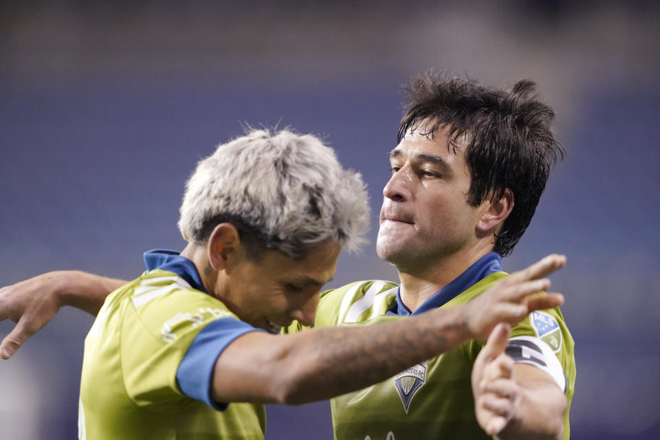 Seattle Sounders' Raul Ruidiaz, left, and Nicolas Lodeiro embrace after the team's 1-0 win over FC Dallas in an MLS playoff soccer match Tuesday, Dec. 1, 2020, in Seattle. (AP Photo/Ted S. Warren)