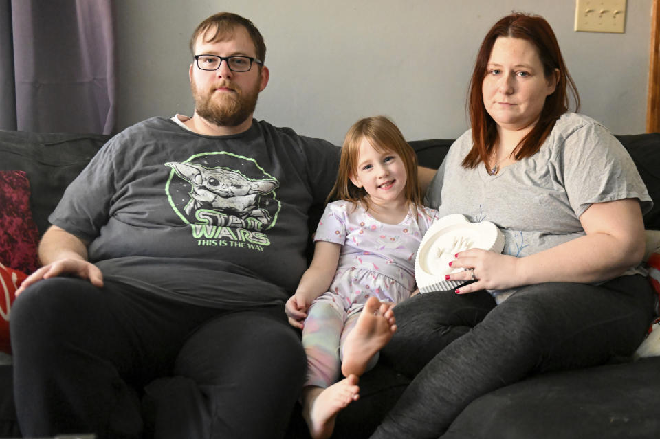 Andrew Weaver, from left, Caitlin Weaver and Jessica Day-Weaver hold a ceramic hand print of daughter, Anastasia, at their home, Thursday, Feb. 2, 2022, in Boardman, Ohio. (AP Photo/Nick Cammett)