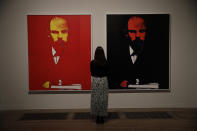 A Tate representative poses for photographs next to the Andy Warhol 1986 piece "Lenin" during a media preview for the exhibition "Andy Warhol" at the Tate Modern gallery in London, Tuesday, March 10, 2020. The exhibition, which runs from March 12 to September 6, features over 100 works spanning the American artist's career in the second half of the 20th century until his death in 1987. (AP Photo/Matt Dunham)