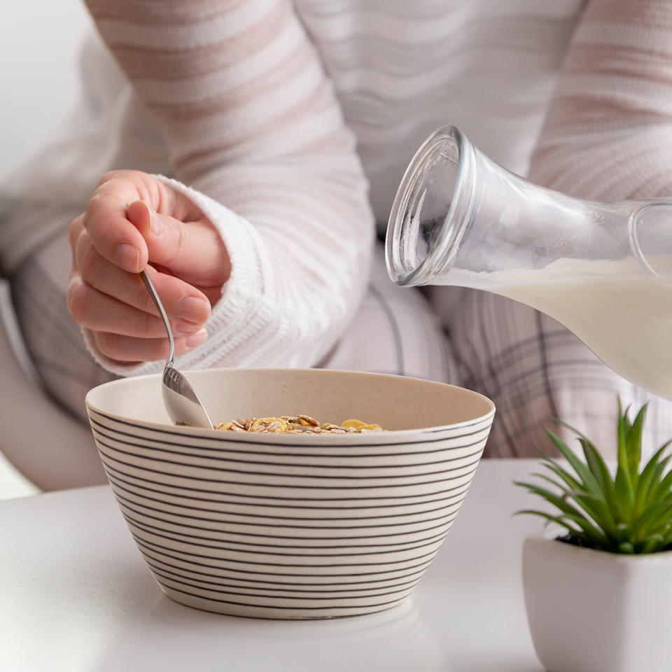 woman pouring milk into cereal bowl