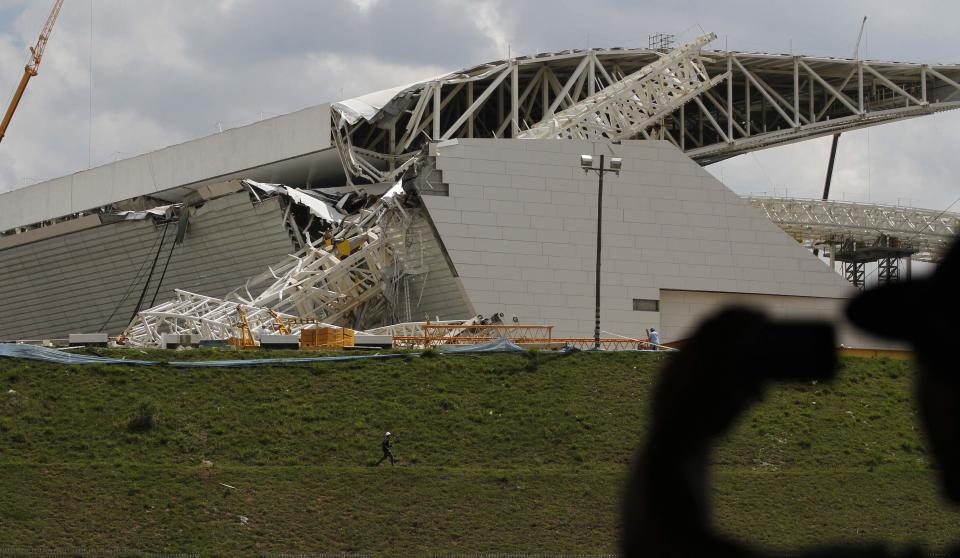 A man takes a picture of a crane that collapsed on the site of the Arena Sao Paulo stadium, known as "Itaquerao", which will host the opening soccer match of the 2014 World Cup, in Sao Paulo