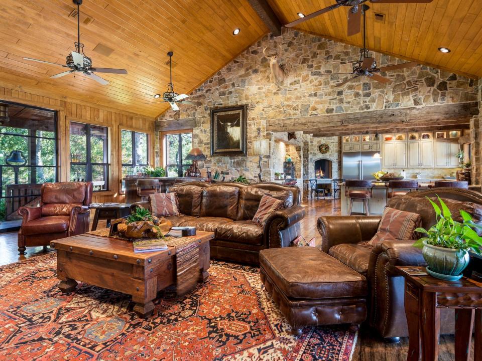 Leather couches back up to a kitchen underneath paneled ceiling and a stone wall at Terry Bradshaw's house.