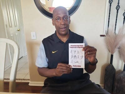 Tim Jackson holds up a copy of his book, "Understanding College Athletics Through the Eyes of College Athletes."