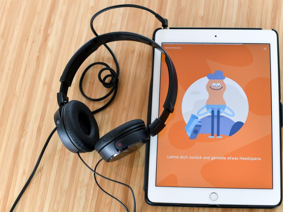 A phone shows the Headspace app and sits next to a pair of headphones.