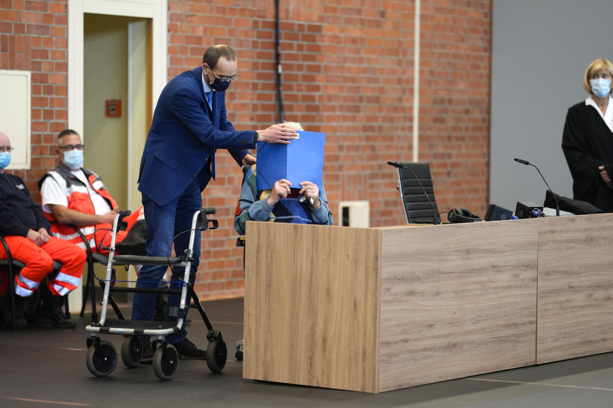 Lawyer Stefan Waterkamp covers the face of accused Josef S. as the arrive at the court room in Brandenburg, Germany, Thursday, Oct. 7, 2021. The 100-year-old man charged as an accessory to murder on allegations that he served as a guard at the Nazis' Sachsenhausen concentration camp during World War II. (AP Photo/Markus Schreiber)