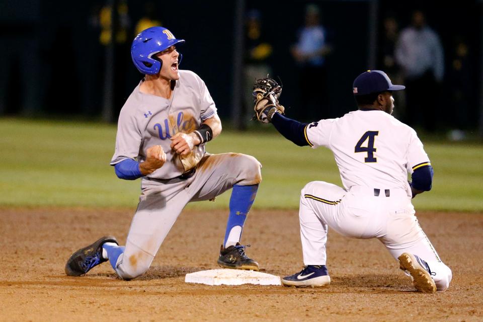UCLA's Ryan Kreidler, left, reacts after he slided safe into second base against Michigan's Ako Thomas during the first inning of an NCAA college baseball tournament super regional game in Los Angeles, Saturday, June 8, 2019. UCLA won 5-4.