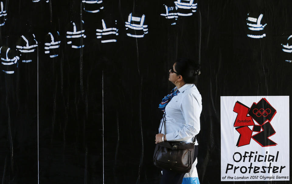 A pedestrian walks past an anti-London 2012 Olympics poster put up by guerrilla artists in east London