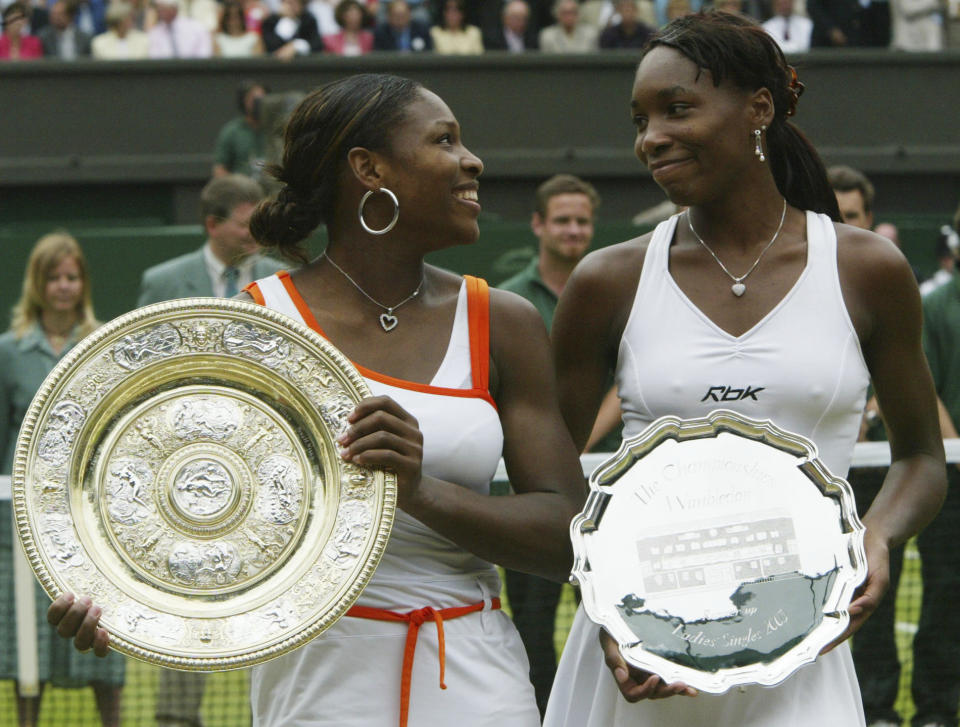 FILE - Serena Williams, left, holds her trophy, as she looks over at her sister Venus, after defeating her in the Women's Singles final on the Centre Court at the All England Lawn Tennis Championships at Wimbledon, London on July 5, 2003. How many total titles have Venus and Serena Willams won at the All England Club? (AP Photo/Dave Caulkin, File)