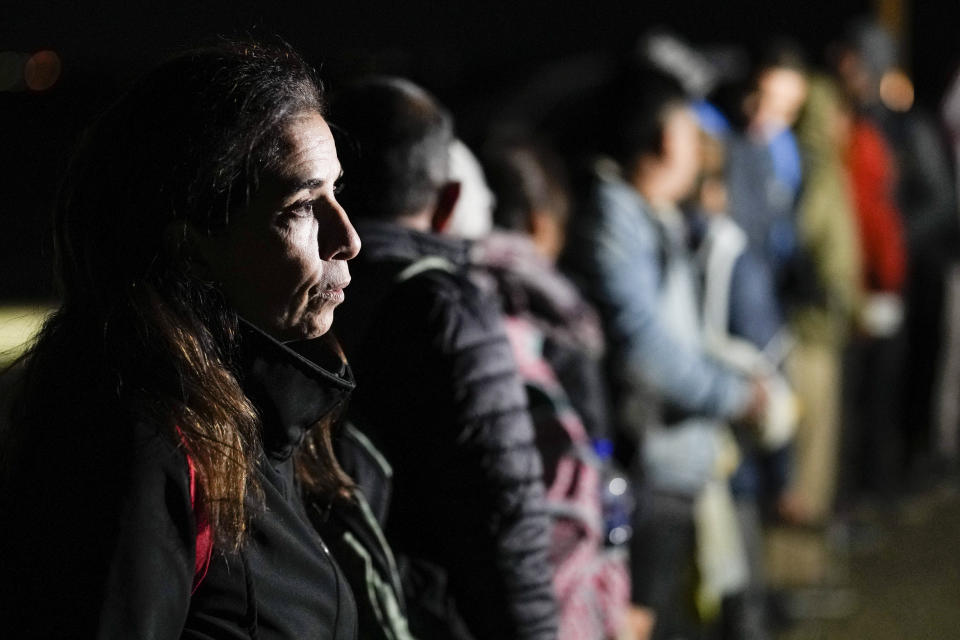 FILE - A woman from Cuba waits with other migrants to be processed to seek asylum after crossing the border into the United States, Friday, Jan. 6, 2023, near Yuma, Ariz. An underground market has emerged for migrants seeking U.S. sponsors since the Biden administration announced last month that it would accept a limited number of people from Venezuela, Cuba, Nicaragua and Haiti. Applicants for the humanitarian parole program need someone in the U.S. to promise to provide financial support for at least two years. (AP Photo/Gregory Bull)