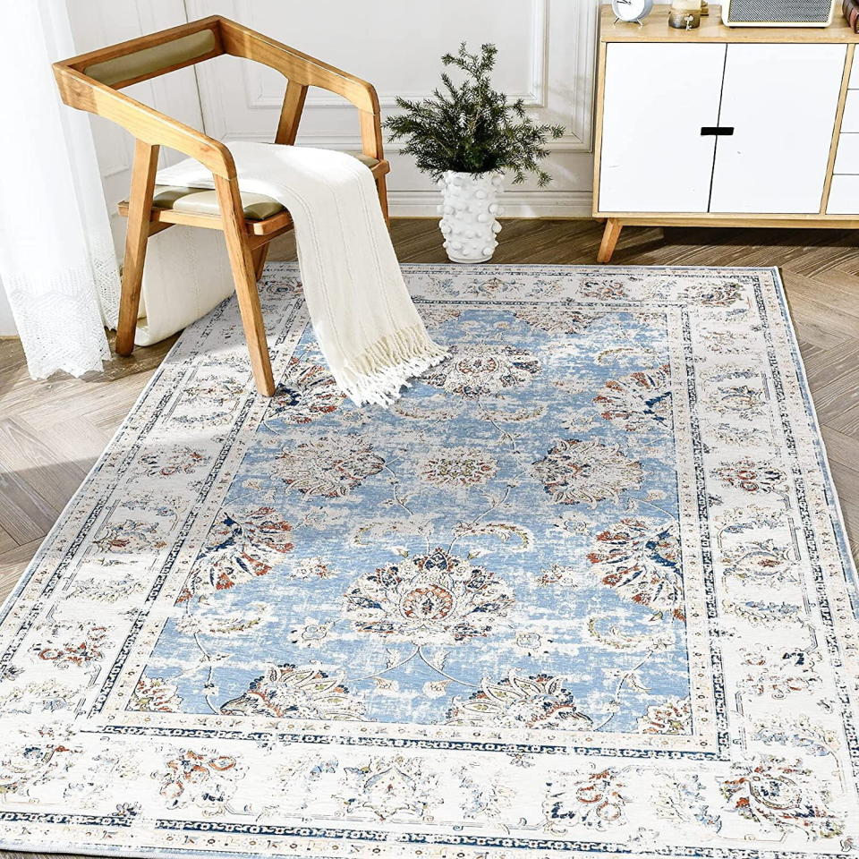 Faded area rug with blue and neutral colors in a living room with a chair on it