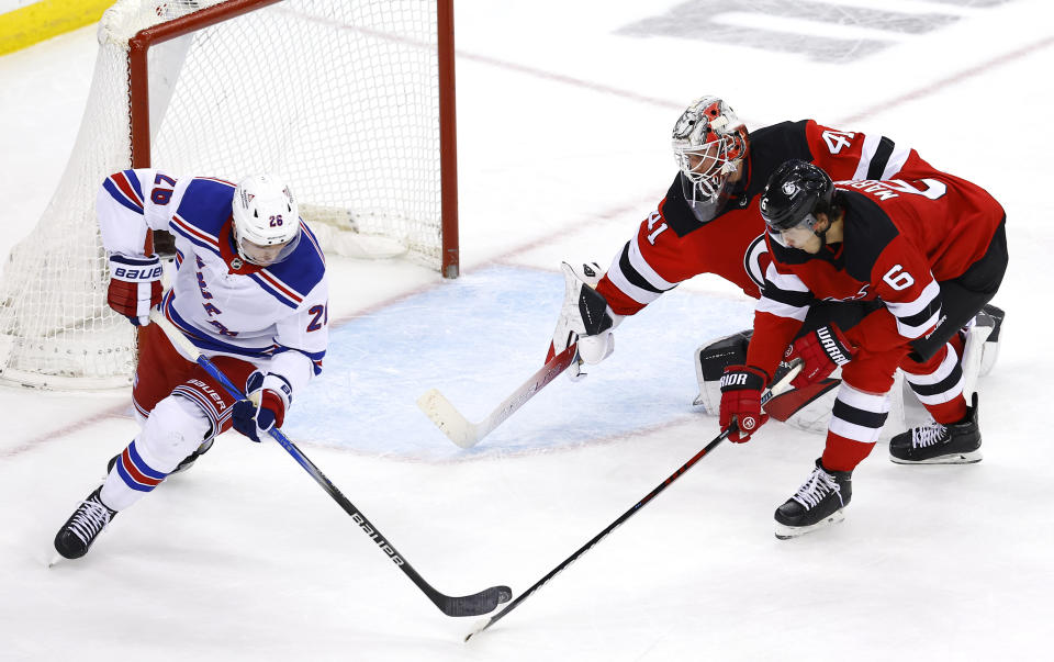 New York Rangers left wing Jimmy Vesey (26) scores a backhanded goal against New Jersey Devils goaltender Vitek Vanecek (41) and defenseman John Marino (6) during the third period of an NHL hockey game Saturday, Nov. 18, 2023, in Newark, N.J. (AP Photo/Noah K. Murray)