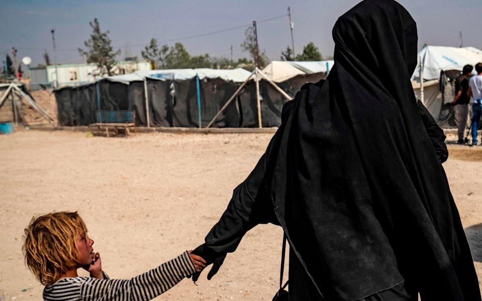  A picture taken on October 17, 2019 shows a French citizen holding a child by the hand at the Kurdish-run al-Hol camp for the displaced where families of Islamic State (IS) foreign fighters are held - AFP