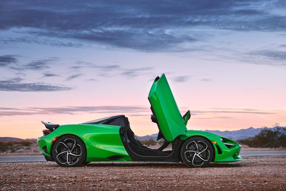 a green sports car with a hood with dinosaur park in the background