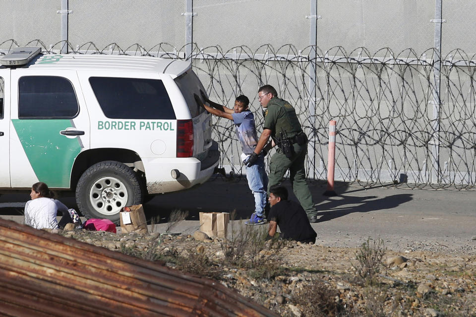 FILE - In this Dec. 15, 2018, file photo, Honduran asylum seekers are taken into custody by U.S. Border Patrol agents after the group crossed the U.S. border wall into San Diego, seen from Tijuana, Mexico. In its efforts to remake the U.S. immigration system, the Trump administration has often stumbled over an obscure law that governs how administrative policies are made. Its latest test is a mammoth proposal to severely limit access to asylum, which invited nearly 80,000 public comments before the Wednesday, July 15, 2020, deadline to offer feedback. (AP Photo/Moises Castillo, File)