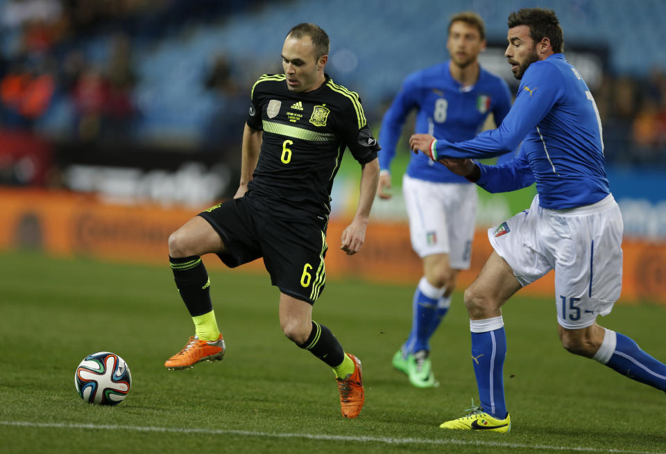 Spain's Andres Iniesta, left steers the ball away from Italy's Andrea Barzagli during a friendly soccer match at the Vicente Calderon stadium in Madrid, Wednesday March 5, 2014. (AP Photo/Paul White)