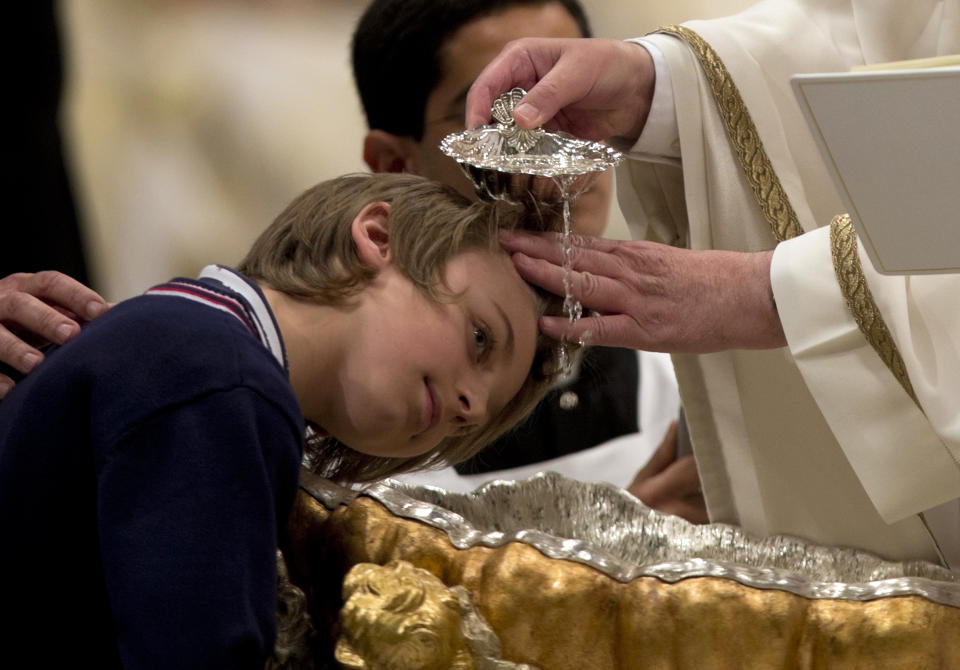 Pope Francis baptizes 10-year-hold Giorgio Capezzuoli during the Easter vigil service in St. Peter's Basilica, at the Vatican Saturday, April 19, 2014. Pope Francis baptized 10 people Saturday as he presided over an Easter Vigil in St. Peter's Basilica, fulfilling a ritual deep in meaning on the most solemn night of the Catholic calendar. Francis urged the priests, bishops, cardinals and ordinary Catholics gathered for the late night service to remember when they first found their faith. "Do I remember it? Have I forgotten it? Look for it. You'll find it. The Lord is waiting." (AP Photo/Alessandra Tarantino)