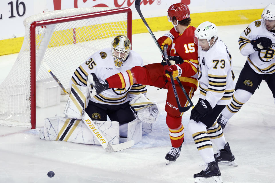 Boston Bruins' Charlie McAvoy (73) keeps Calgary Flames' Dryden Hunt, away from the puck and Boston goalie Linus Ullmark during the first period of an NHL hockey game Thursday, Feb. 22, 2024, in Calgary, Alberta. (Larry MacDougal/The Canadian Press via AP)