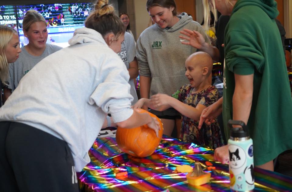 Jacksonville University women's lacrosse members help Lucy Donmoyer carve a pumpkin last fall during a Halloween party at the team's facility. JU adopted Lucy through Friends of Jaclyn, a program that connects college teams with pediatric cancer victims. Lucy passed away in the fall of 2023.