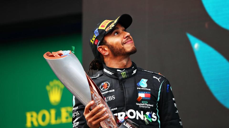 sir lewis hamilton smiles as he holds a trophy at the 2020 turkish grand prix, where he celebrates winning his record equalling seventh world drivers' title