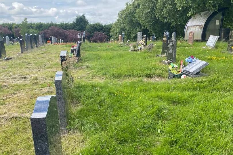 Graves surrounded by long grass viewed from side at Carlton Cemetery, Carlton, Nottinghamshire