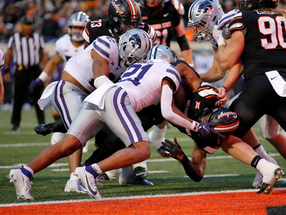 Oklahoma State’s Ollie Gordon II (0) scores a touchdown as <a class="link " href="https://sports.yahoo.com/ncaaf/teams/kansas-st/" data-i13n="sec:content-canvas;subsec:anchor_text;elm:context_link" data-ylk="slk:Kansas State;sec:content-canvas;subsec:anchor_text;elm:context_link;itc:0">Kansas State</a>’s Kobe Savage (2) and Marques Sigle (21) defend in the the first half of the college football game between the Oklahoma State University Cowboys and the <a class="link " href="https://sports.yahoo.com/ncaaf/teams/kansas-st/" data-i13n="sec:content-canvas;subsec:anchor_text;elm:context_link" data-ylk="slk:Kansas State Wildcats;sec:content-canvas;subsec:anchor_text;elm:context_link;itc:0">Kansas State Wildcats</a> at Boone Pickens Stadium in Stillwater. Okla., Friday, Oct. 6, 2023.