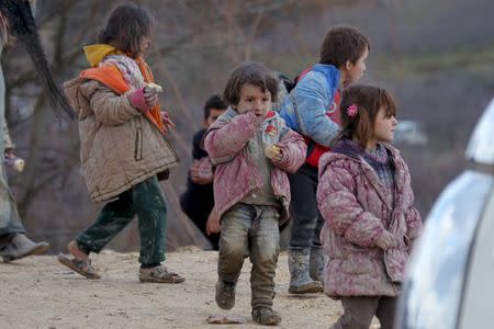 Internally displaced children, covered with mud, wait with their families as they are stuck in the town of Khirbet Al-Joz, in Latakia countryside, waiting to get permission to cross into Turkey near the Syrian-Turkish border, Syria, February 7, 2016. REUTERS/Ammar Abdullah