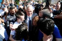 Members of the media surround leader of Blue and White party, Benny Gantz as he huddles with his family members after he voted in Israel's parliamentary election at a polling station in Rosh Ha'ayin, Israel