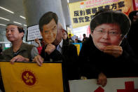 Protesters demanding universal pension hold paper cutouts of Hong Kong Chief Executive Leung Chun-ying (C) and resigned Chief Secretary Carrie Lam (R) ahead of Leung's policy address, outside Legislative Council in Hong Kong, China January 18, 2017. REUTERS/Bobby Yip