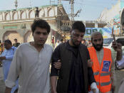 Pakistani volunteers help an injured person at the site of a bomb explosion in an Islamic seminary, in Peshawar, Pakistan, Tuesday, Oct. 27, 2020. A powerful bomb blast ripped through the Islamic seminary on the outskirts of the northwest Pakistani city of Peshawar on Tuesday morning, killing some students and wounding dozens others, police and a hospital spokesman said. (AP Photo/Muhammad Sajjad)