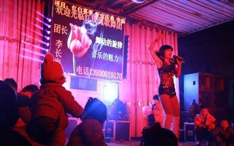 Children and adults watch a striptease show at a funeral in Cheng'an county, Hebei Province, China. - Credit: Zhang/Global Times