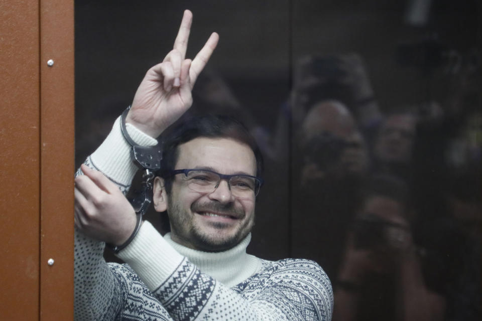 FILE - Russian opposition activist and former municipal deputy of the Krasnoselsky district Ilya Yashin gestures, smiling, as he stands in a defendant's cubicle in a courtroom, prior to a hearing in Moscow, Russia, on Dec. 9, 2022. Most Russian opposition figures are either in prison at home or are in exile abroad. But they vow that they will still put up a fight against President Vladimir Putin as he seeks yet another term in office in an election scheduled for March.(Yury Kochetkov/Pool via AP, Pool, File)