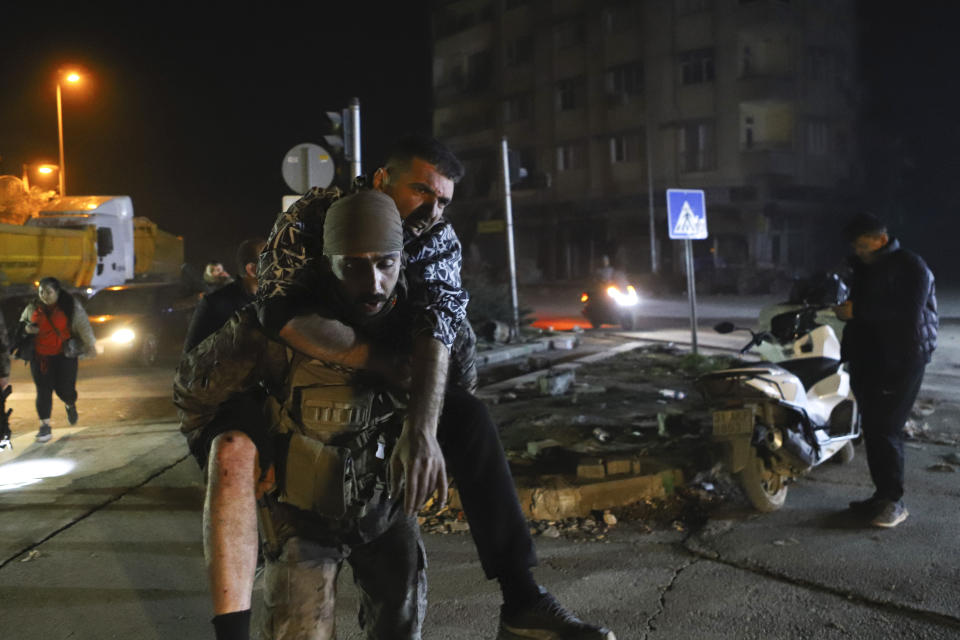 A soldier carries a man after being injured in the latest earthquake in Hatay, Turkey, Monday, Feb. 20, 2023. A new 6.4 magnitude earthquake on Monday killed three people and injured more than 200 in parts of Turkey that were laid waste two weeks ago by a massive quake that killed tens of thousands. Officials said more buildings collapsed, trapping occupants, and several people were injured in both Turkey and Syria. (Efekan Akyuz/Depo Photos via AP)