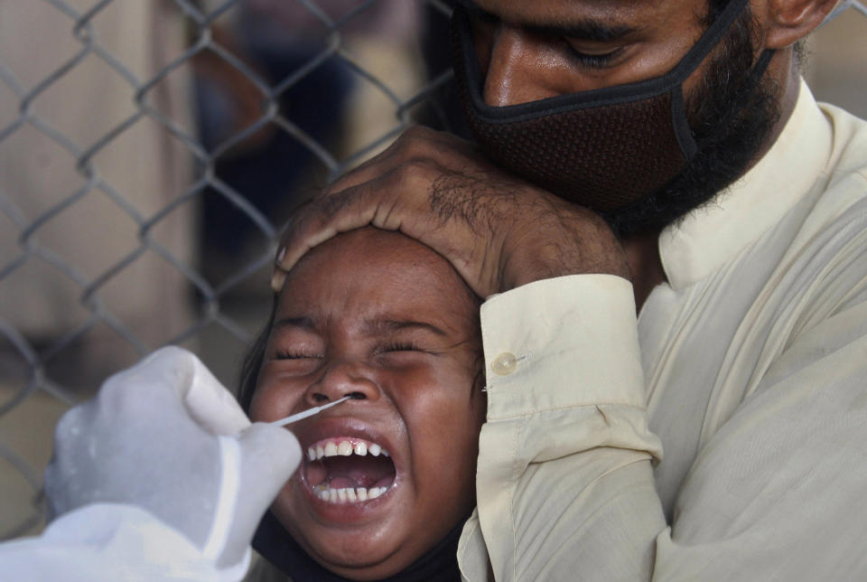 Image: A girl reacts while getting a nasal swab sample at a testing and screening facility for the new coronavirus in a hospital in Karachi, Pakistan (Fareed Khan / AP)