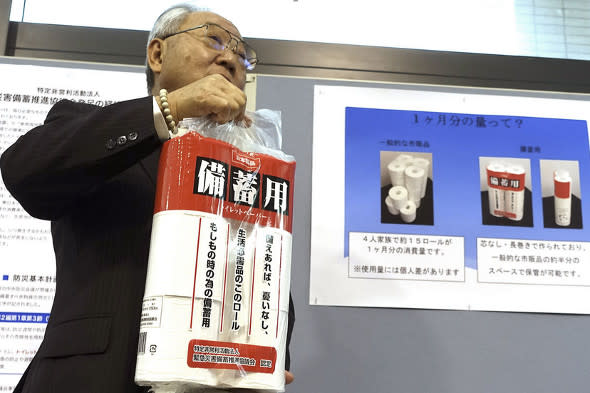 Government official Toshiyuki Hashimoto holds up a pack of toilet paper