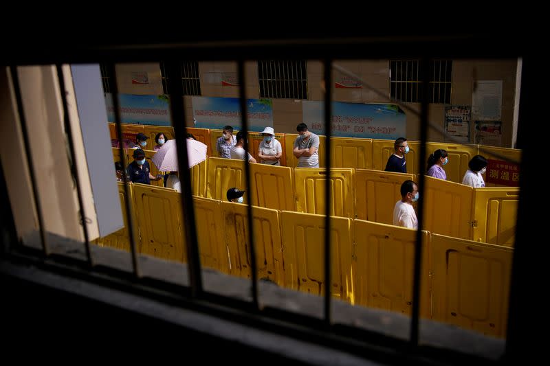 Residents wearing face masks line up for nucleic acid testings at a residential compound in Wuhan