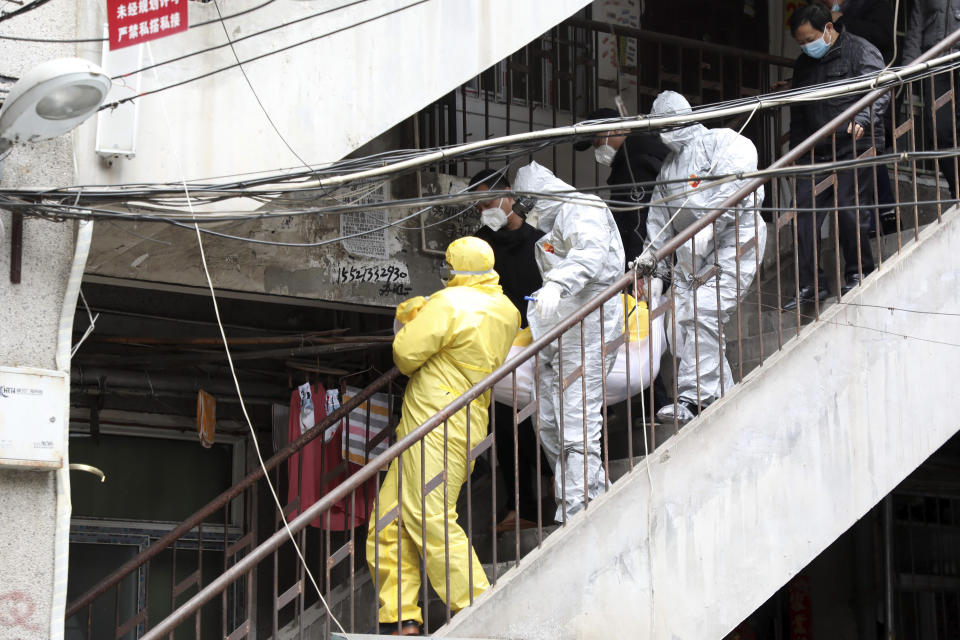 In this Feb. 1, 2020, photo, funeral home workers remove the body of a person suspect to have died from a virus outbreak from a residential building in Wuhan in central China's Hubei Province. The Philippines on Sunday reported the first death from a new virus outside of China, where authorities delayed the opening of schools in the worst-hit province and tightened quarantine measures in a city that allow only one family member to venture out to buy supplies. (Chinatopix via AP)