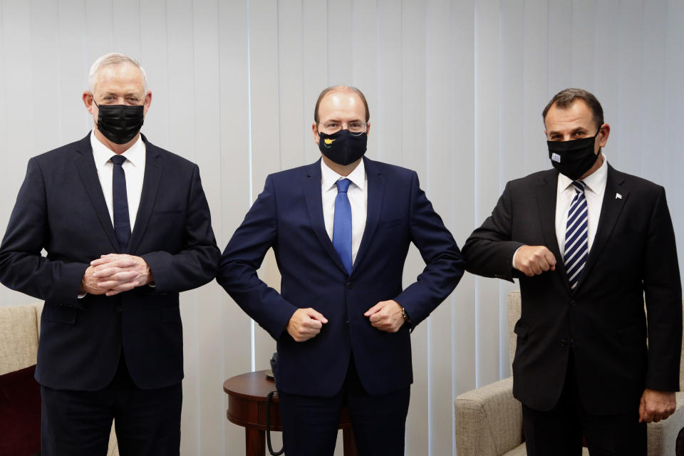 Cyprus' Defense Minister Charalambos Petrides, center, shares an elbow bump with his Israeli counterpart Benny Ganz, left, on his first visit to Cyprus and his Greek counterpart Nikolaos Panagiotopoulos, right, ahead of their meeting aimed at bolstering defense ties in the Cypriot capital Nicosia, Cyprus, on Thursday, Nov. 12, 2020. Greece, Cyprus and Israel have in recent years forged a closer partnership that they say aims to strengthen security and stability in the eastern Mediterranean. (AP Photo/Petros Karadjias)