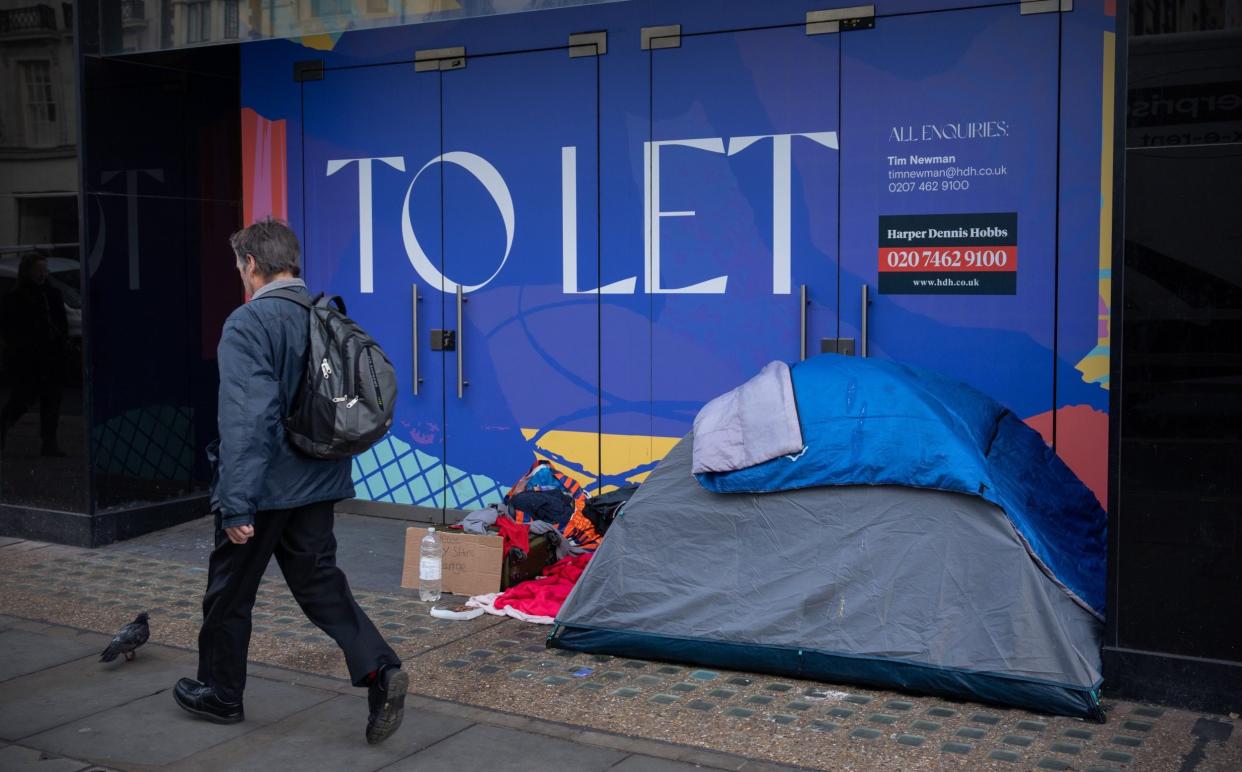 A man walks past a homeless persons tent - Carl Court/Getty Images