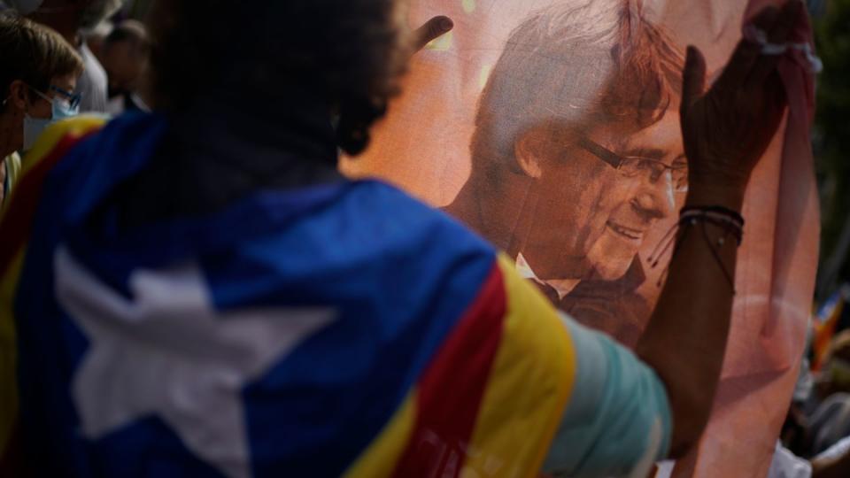 Ein Mann hält ein bedrucktes Tuch mit dem Bild des ehemaligen katalanischen Regierungschefs Puigdemont während eines Protests vor dem italienischen Konsulat in Barcelona.