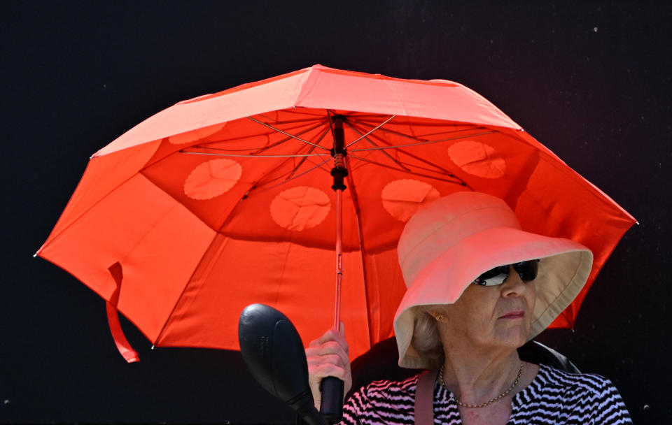A spectator shelters from the sun beneath an umbrella as they wait to watch the women's singles final tennis match at the Rothesay Eastbourne International tennis tournament in Eastbourne, southern England, on June 29, 2024. (Photo by Glyn KIRK / AFP) (Photo by GLYN KIRK/AFP via Getty Images)