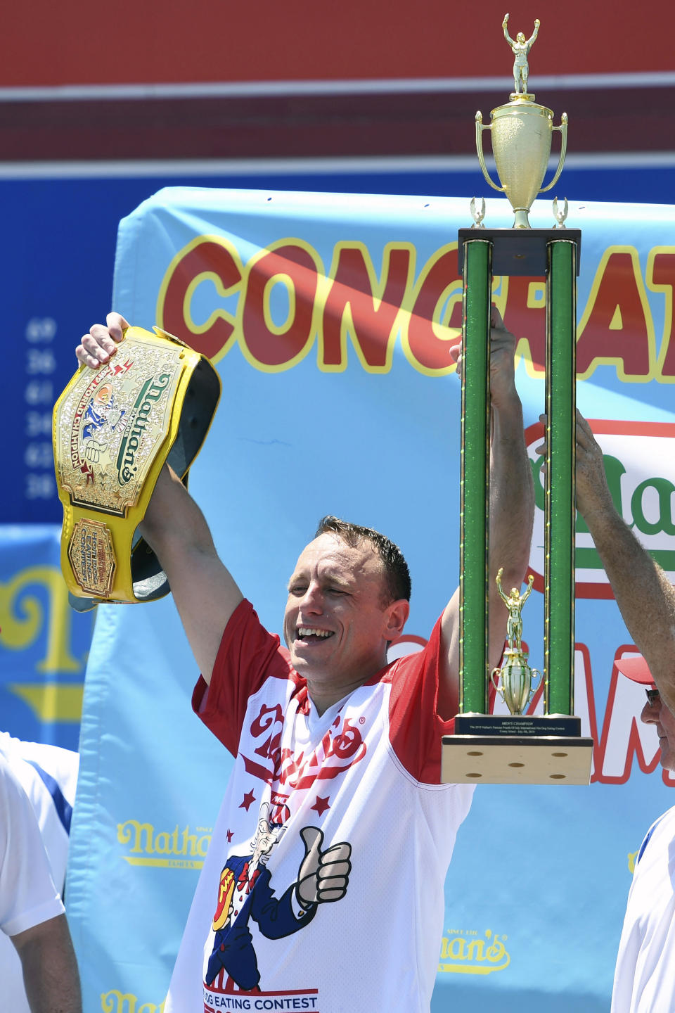 Joey Chestnut raises his trophy and belt after winning the men's competition of Nathan's Famous July Fourth hot dog eating contest, Thursday, July 4, 2019, in New York's Coney Island. (AP Photo/Sarah Stier)